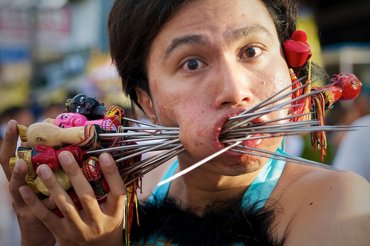 homme se transperçant les joues au festival végétarien phuket